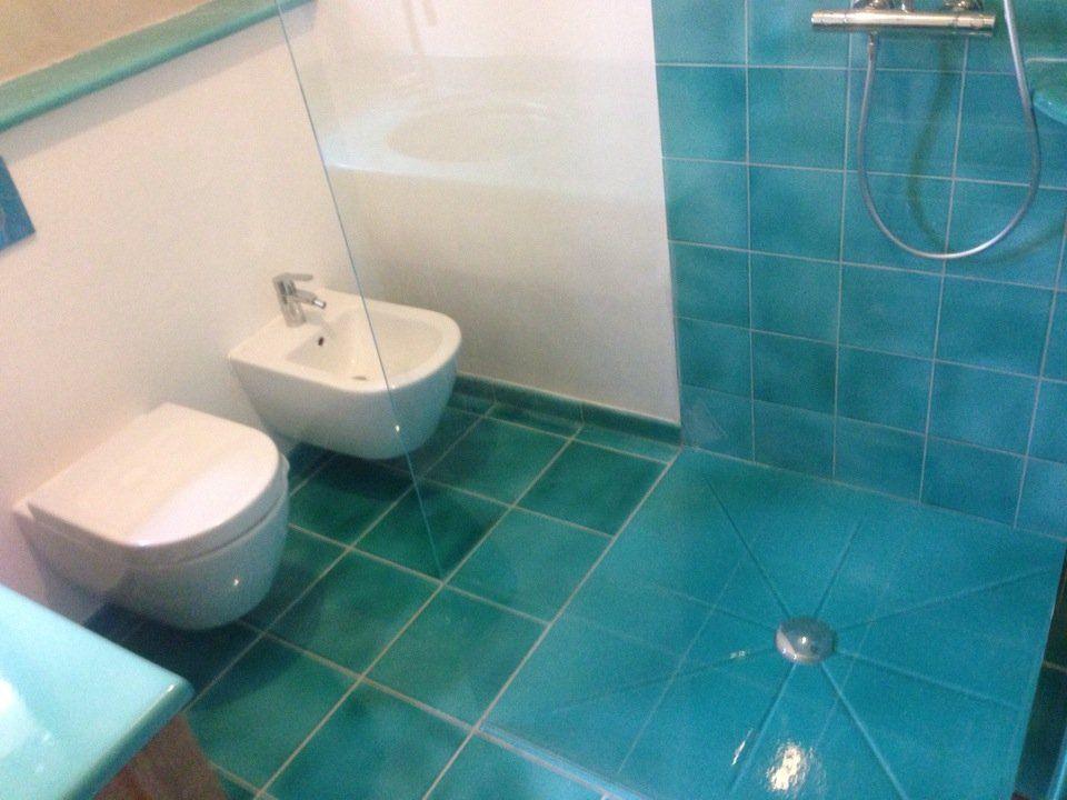 Douche à l'italienne carrelée turquoise avec bonde centrale et paroi vitrée