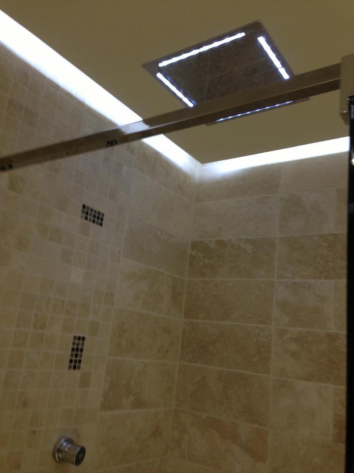 Ciel de pluie encastré à éclairage LED dans une douche en travertin